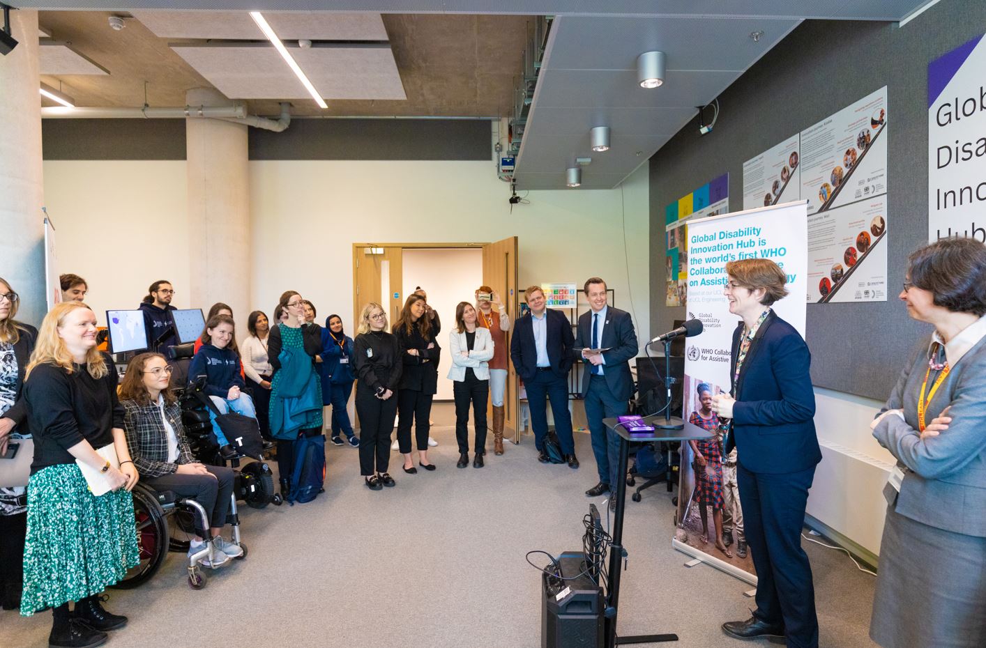 Cathy speaks at opening of the GDI Hub lab opening in front of UCL WHO Collaborating Centre on Assistive Technology banner