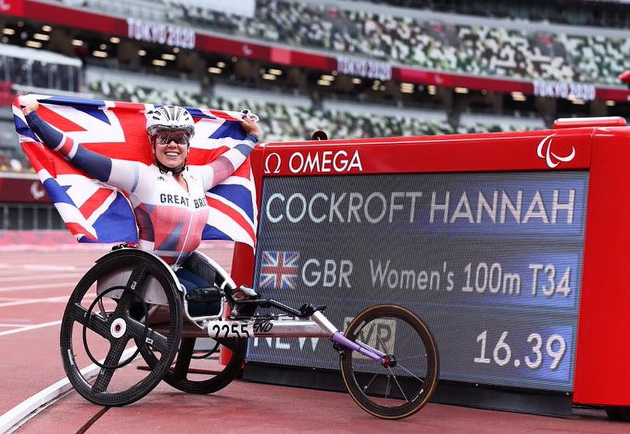 "A woman with long blonde hair is sat in a wheelchair in front of Windsor Castle, she is wearing a black and white checked jacket and a white dress. She is holding a red OBE ribbon up, and is smiling at the camera.</p>
<p>A woman sat in a racing wheelchair on an athletics track, next to a timing board. She is holding a Union flag behind her and is wearing a red white and blue long sleeved top and a helmet with a visor covering her face. The screen reads 'Hannah Cockroft, GBR, Womens 100m T34, New WR, 16.39'."