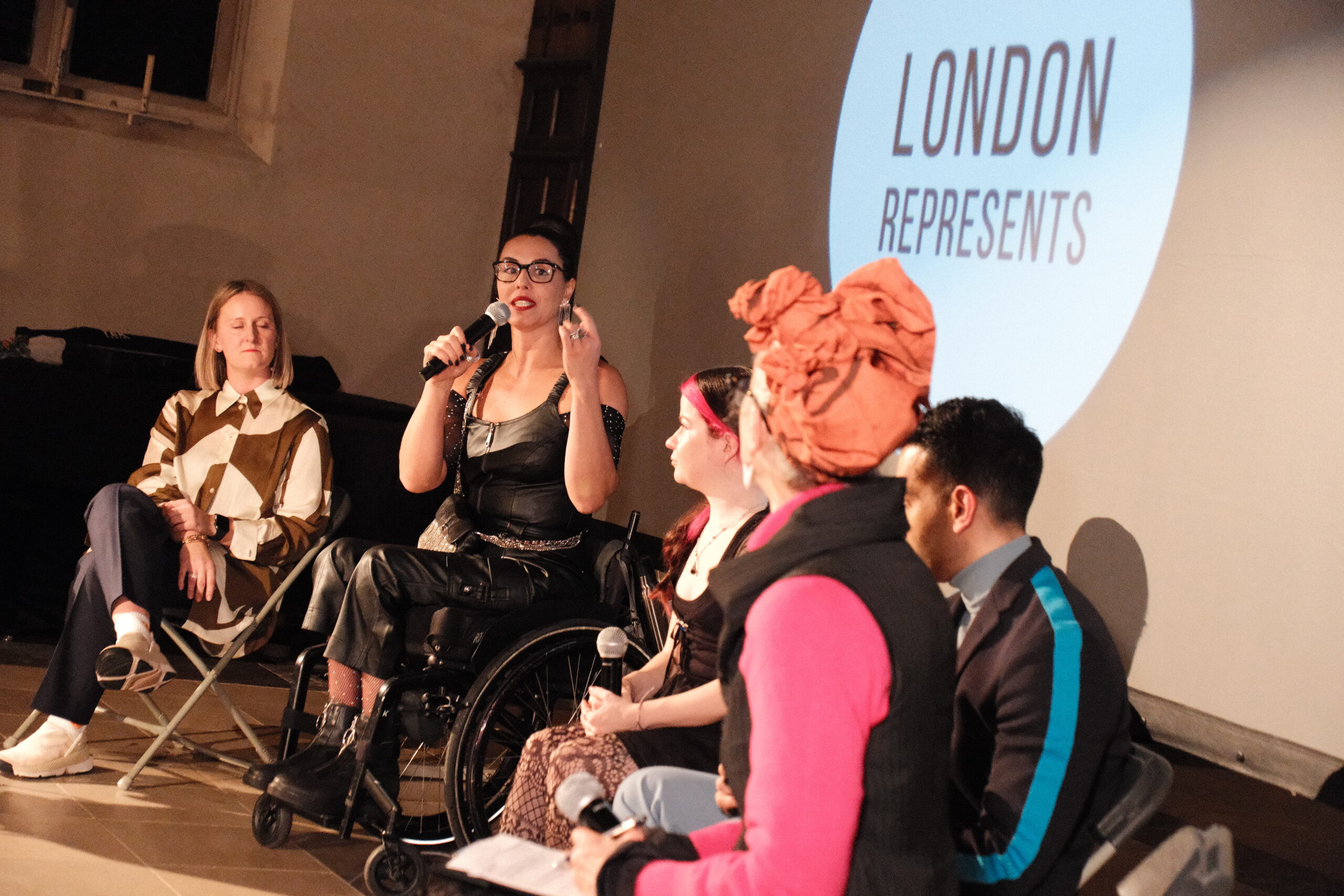 A panel discussion about disability in a church with 5 people involved. Written London Represents in a screen at the back.