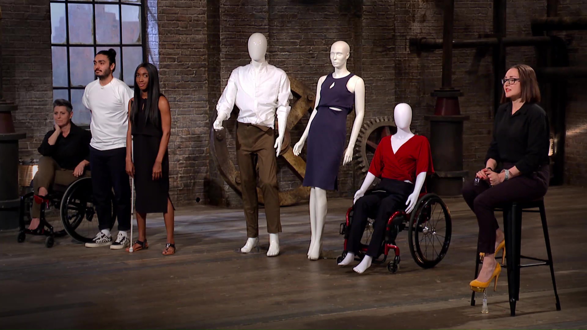An image of a group of people on dragons den, victoria sits on a stool alongside mannequins, one of which is in a wheelchair